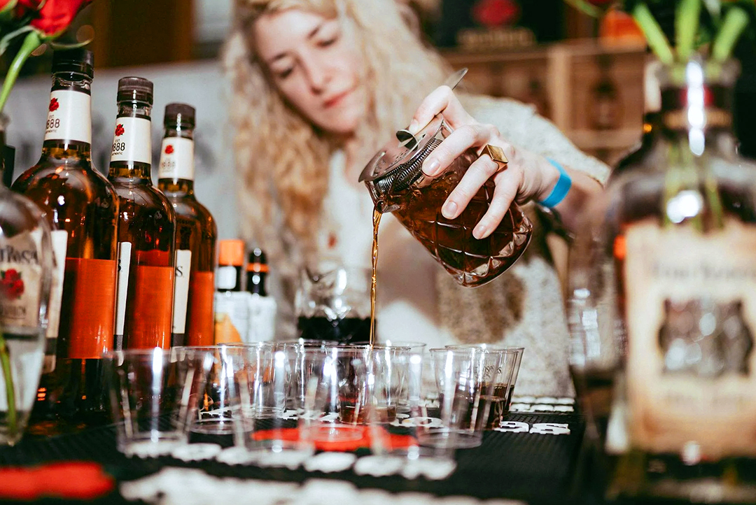 A bartender pouring a cocktail.